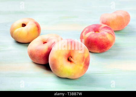 A photo of vibrant organic flat saturn peaches on a teal background with a place for text Stock Photo