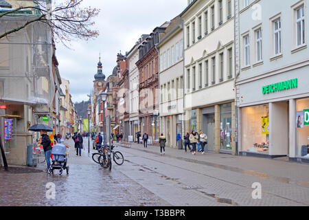 Main street with different stores in old buildings and few people in historical city center on a rainy day Stock Photo