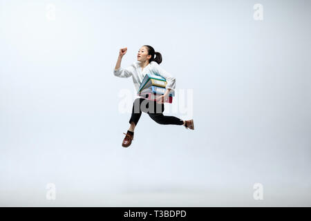 Try hard for your family. Happy woman working at office, jumping and dancing in casual clothes or suit isolated on white studio background. Business, start-up, working open-space concept. Stock Photo