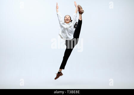 Growth to the new result and emotions. Woman working at office, jumping and dancing in casual clothes or suit isolated on white studio background. Business, start-up, working open-space concept. Stock Photo