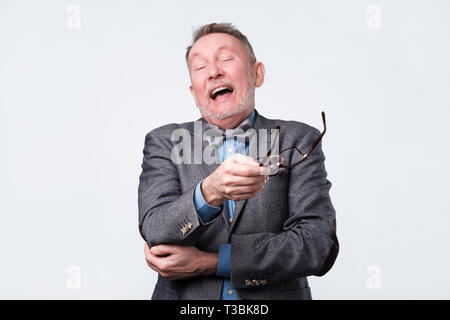 Senior man in red shirt laughs. Positive facial emotion. Studio shot Stock Photo