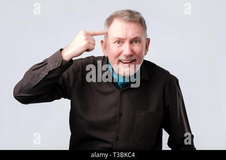 Handsome middle age hoary senior man smiling pointing to head with one finger. Waht is on your mind or are you crazy concept. Stock Photo