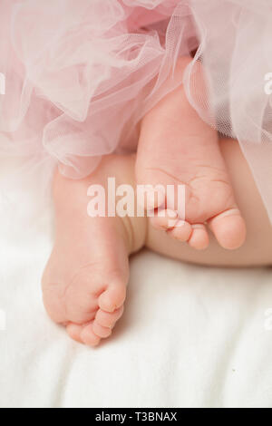 Baby girls feet with tulle dress on white Stock Photo