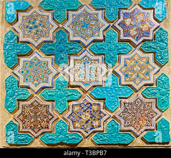 Historic tilework with bright floral patterns on the octagonal stellar tiles and the relief animalistic ornaments on the blue cross-shaped tiles, Tehr Stock Photo