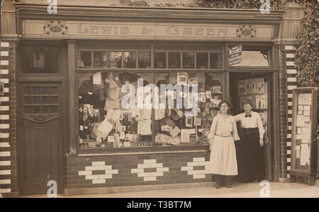 Vintage Photographic Postcard Showing The Staff of The Lewis & Green Shop at No 59. Items of Clothing in The Shop Window. Sign Above The Door Which States 'Madame Westoby's High Class Registry Office For Servants'. Stock Photo