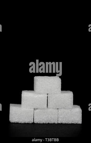 Pyramid of white sugar cubes isolated against a black background Stock Photo