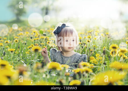 Little baby girl playing outdoors in spring flowers meadow Stock Photo