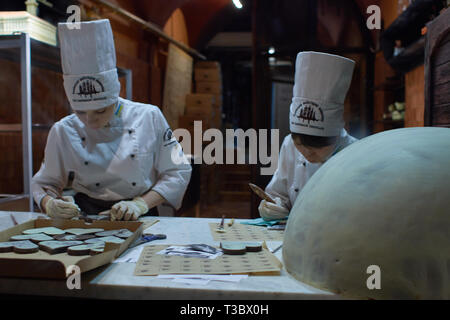 Lviv, Ukraine. 13 March 2016. Person working inside of the Lviv Homemade Chocolate Factory. Store view through the shop window, woman producing chocol Stock Photo