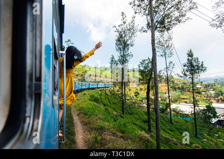 Woman enjoying the train ride through Sri Lanka tea plantations Stock Photo