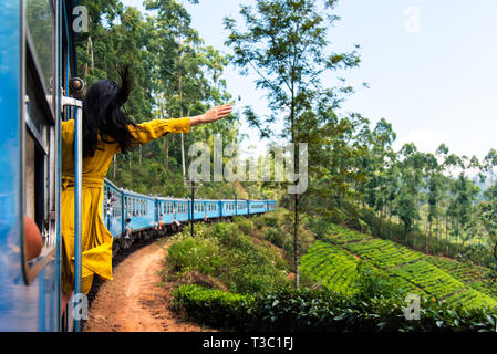 Woman enjoying the train ride through Sri Lanka tea plantations Stock Photo
