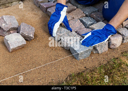 cobblestone installation - paver laying granite stone pavers Stock Photo