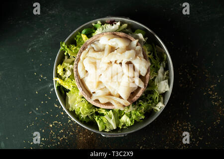 high angle view of some bowls with the ingredients to prepare xato, a catalan salad with desalinated salt cod and escarole endive, on a rustic dark gr Stock Photo