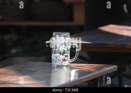 Abandoned empty beer mug on beer garden table. Stock Photo