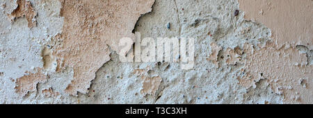Old grungy weathered wall background texture. Beige dirty peeled plaster wall with falling off flakes of paint Stock Photo