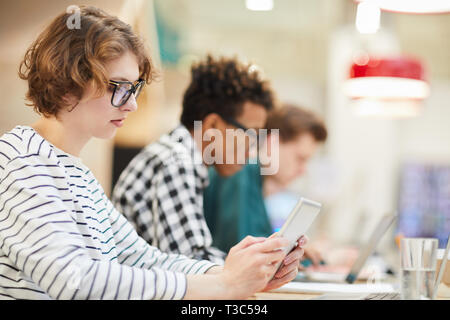 Thoughtful student girl using tablet in university Stock Photo