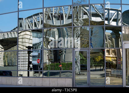 Distorted reflections of iron viaduct with iron & stone columns of the elevated Metro Line 6 seen in a mirror-glazed office building beside the tracks Stock Photo