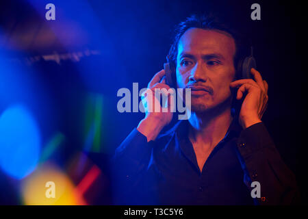 Asian handsome man standing and listening to his favourite music on headphones Stock Photo