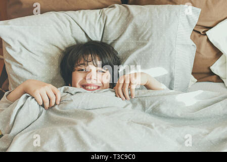 happy child lying on the bed after wake up Stock Photo