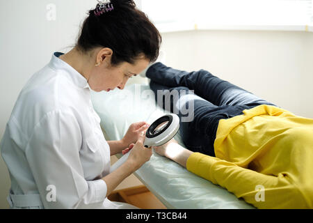 Dermatologist using a professional magnifying glass while doing skin examination, Checking benign moles on hand. Dermatologist examining birthmarks an Stock Photo