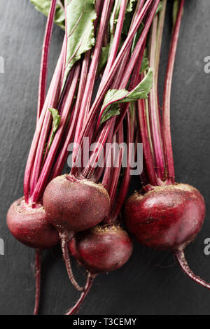 whole young beets with tops on the table, on a black background. space for text Stock Photo