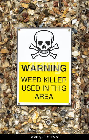 Weed killer usage warning sign attached to pebble dashed wall Stock Photo