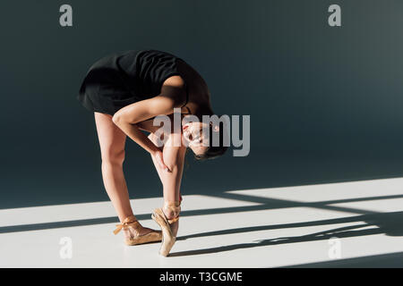 young ballerina in black dress stretching in sunlight Stock Photo