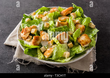 Caesar salad with lettuce,chicken and croutons on black background. Stock Photo