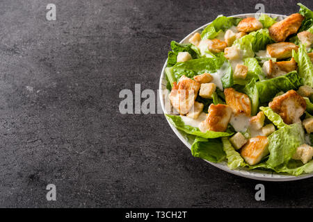 Caesar salad with lettuce,chicken and croutons on black background. Copyspace Stock Photo