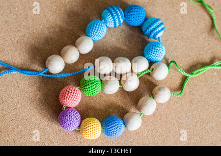 Necklace made from knitted beads and toys for the baby sitting in a sling. Knitted beads. Sling necklace. Stock Photo