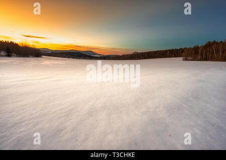Snow plain under the orange sunset sky. Stock Photo