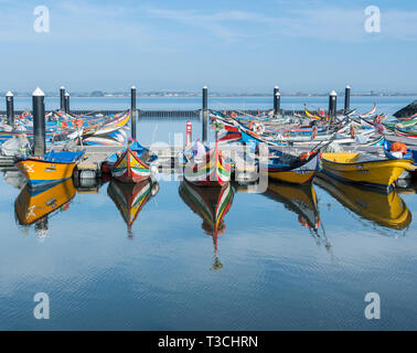 The brightly coloured traditional fishing boats in the harbour in the village of Torreira, Portugal. Stock Photo