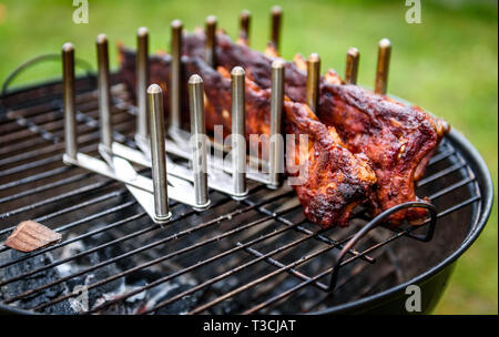 Baby Back Spare Ribs Roast on BBQ barbecue kettle grill. Home made pork ribs on a grill using low and slow method. Grilling outdoors in nature at fami Stock Photo