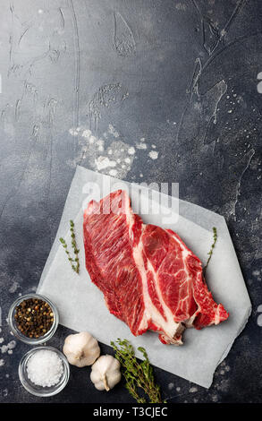 Macro fresh cut of beef meat on gray background with herbs, salt and pepper. Free space for text. Top view. Concept of fresh food Stock Photo