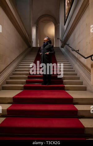 Woman Standing on Red Carpet in Staircase. Stock Photo
