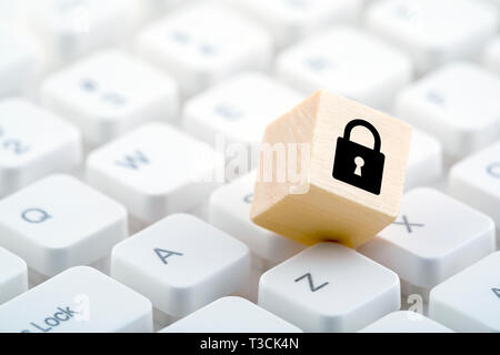 Wooden block with lock graphic on computer keyboard. Computer security concept. Stock Photo