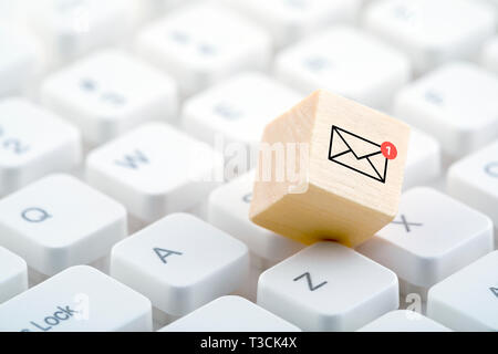 New email graphic on wooden block over computer keyboard Stock Photo