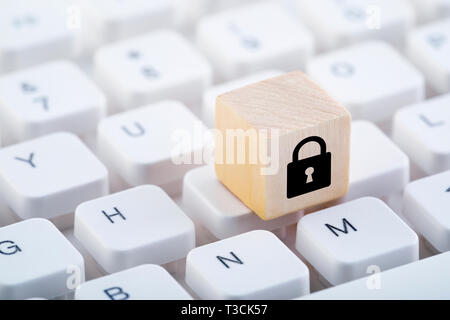 Wooden block with lock graphic on computer keyboard. Computer security concept. Stock Photo
