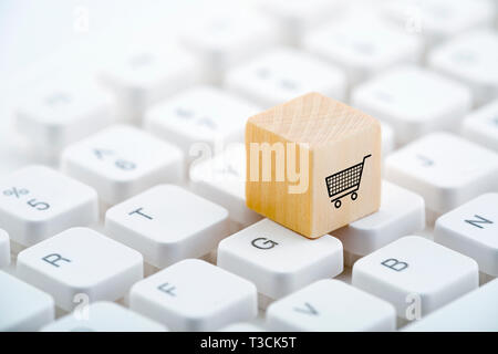 Wooden block with shopping cart graphic on computer keyboard. Online shopping concept. Stock Photo