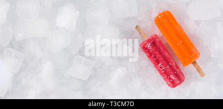 Orange and strawberry popsicles on ice cubes. Panoramic view Stock Photo