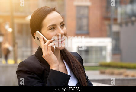 Young businesswoman uses smartphone, woman is walking around the city Stock Photo