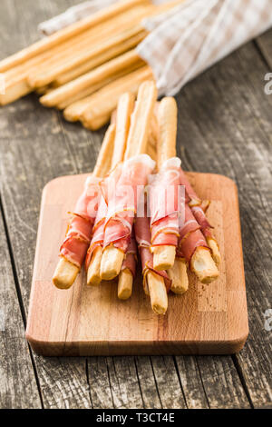 Parma ham prosciutto with grissini breadsticks on cutting board. Stock Photo