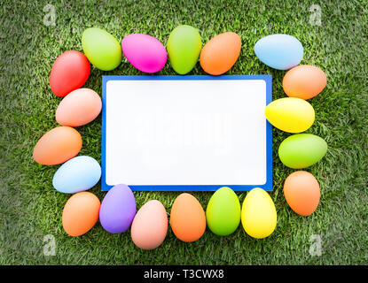 Blank Easter greeting card framed with pastel colored eggs on top of green grass Stock Photo