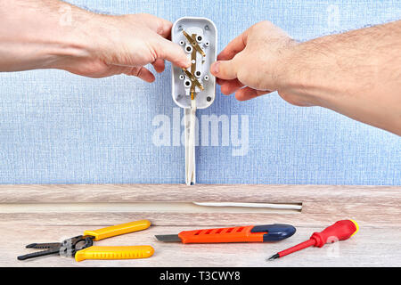 Installing euro wall plug socket by electrician, there are working tools on the floor. Stock Photo
