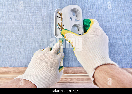 Electrician is putting new           pattress box on wall socket,  installing wall plug socket. Stock Photo