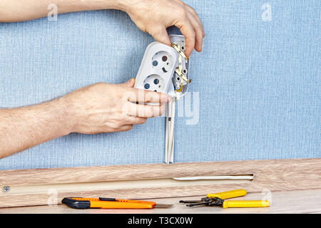Electrician is putting new pattress box on electrical socket with hand tools on the floor. Stock Photo