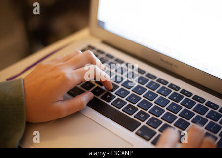 Close-up of a hand typing on a laptop keyboard Stock Photo