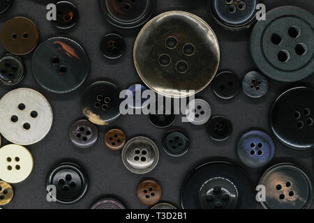 Various old and dark plastic and metal clothes buttons on grey background Stock Photo