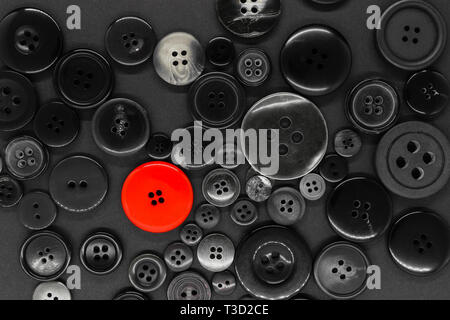 Various black and white, plastic and metal clothes buttons background with one red button Stock Photo