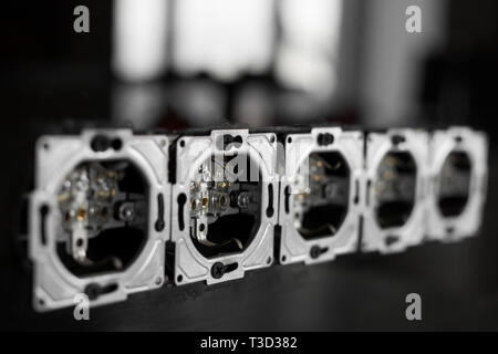 Five outlets in line, disassembled and mounted in black glass wall. Stock Photo