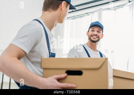 selective focus of two movers transporting cardboard boxes in apartment Stock Photo